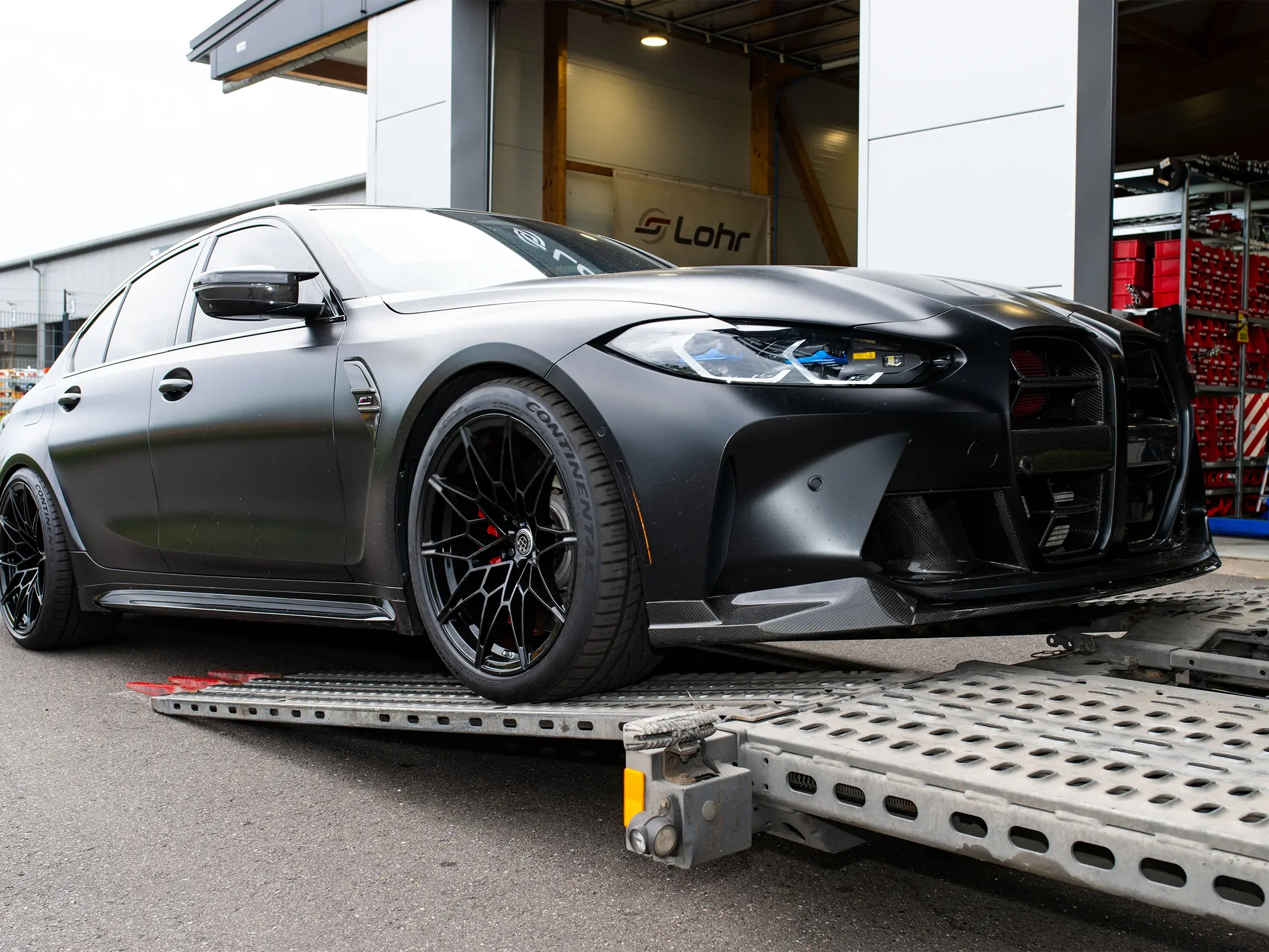 Schwarzes Sportauto mit mattem Finish fährt auf einem Transportanhänger.
